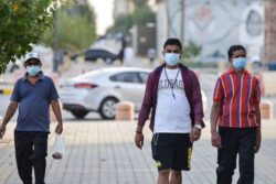 Mask-clad men walk along the promenade of Tahlia street in the centre of Riyadh