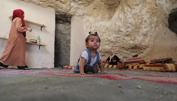 A young baby crawls on the floor in a cave.Palestinian family living in cave home receives demolition notice from Israel