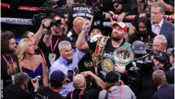 Tyson Fury defeats Deontay Wilder and celebrates in the ring with his belt and his entourage