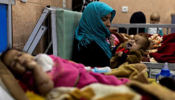 In Afghanistan a young mother holds her one-year-old baby, at the malnutrition ward for infantsat a Children's hospital in Kabul waiting for free medication that the US will not release