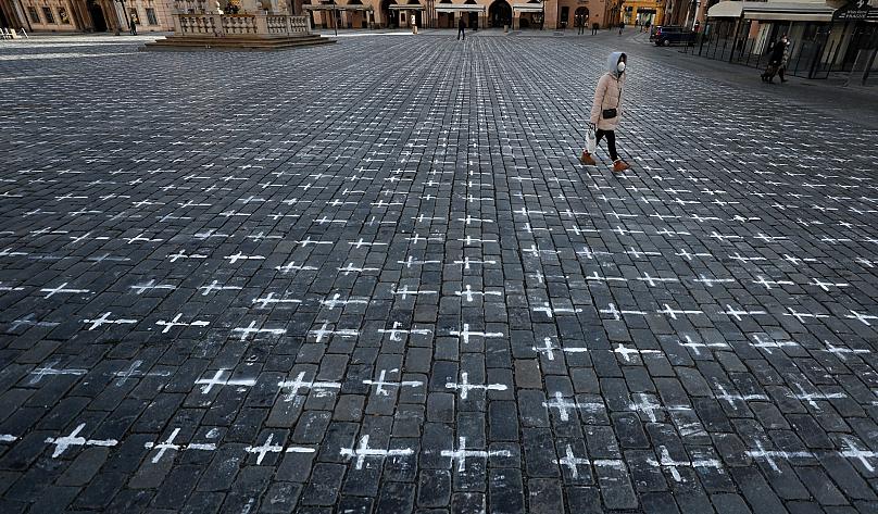A woman walks at the Old Town Square in Prague, Czech Republic. A group of activists painted the crosses to criticise the government's response to the coronavirus pandemic