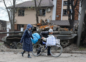 Mariupol has fallen - Local civilians walk past a tank destroyed during heavy fighting in Mariupol