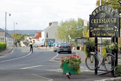 Groups huddle together as family and friends lay floral tributes in Creeslough