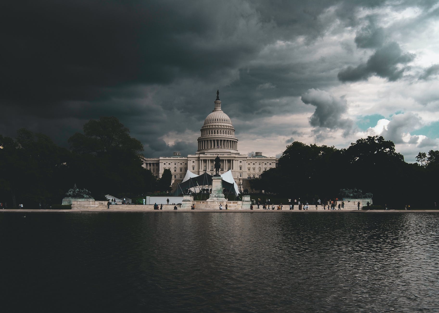 A pictures of The US Senate looking serene at night - The Dome building near body of water under cloudy sky