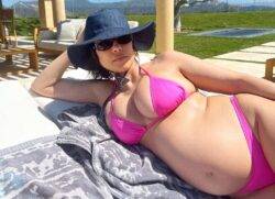 Kourtney Kardashian glows as she cradles growing baby bump in bright pink bikini