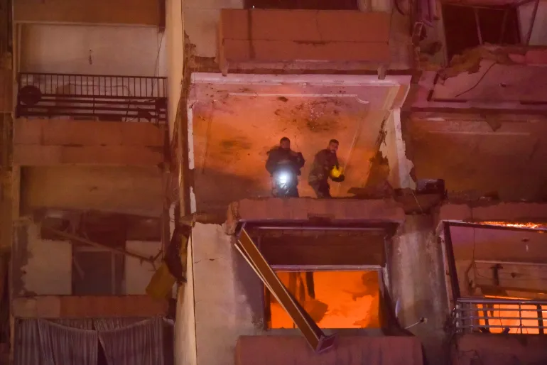 Firefighters search for survivors inside an apartment building hit by an Israeli air strike in Beirut’s Kola district