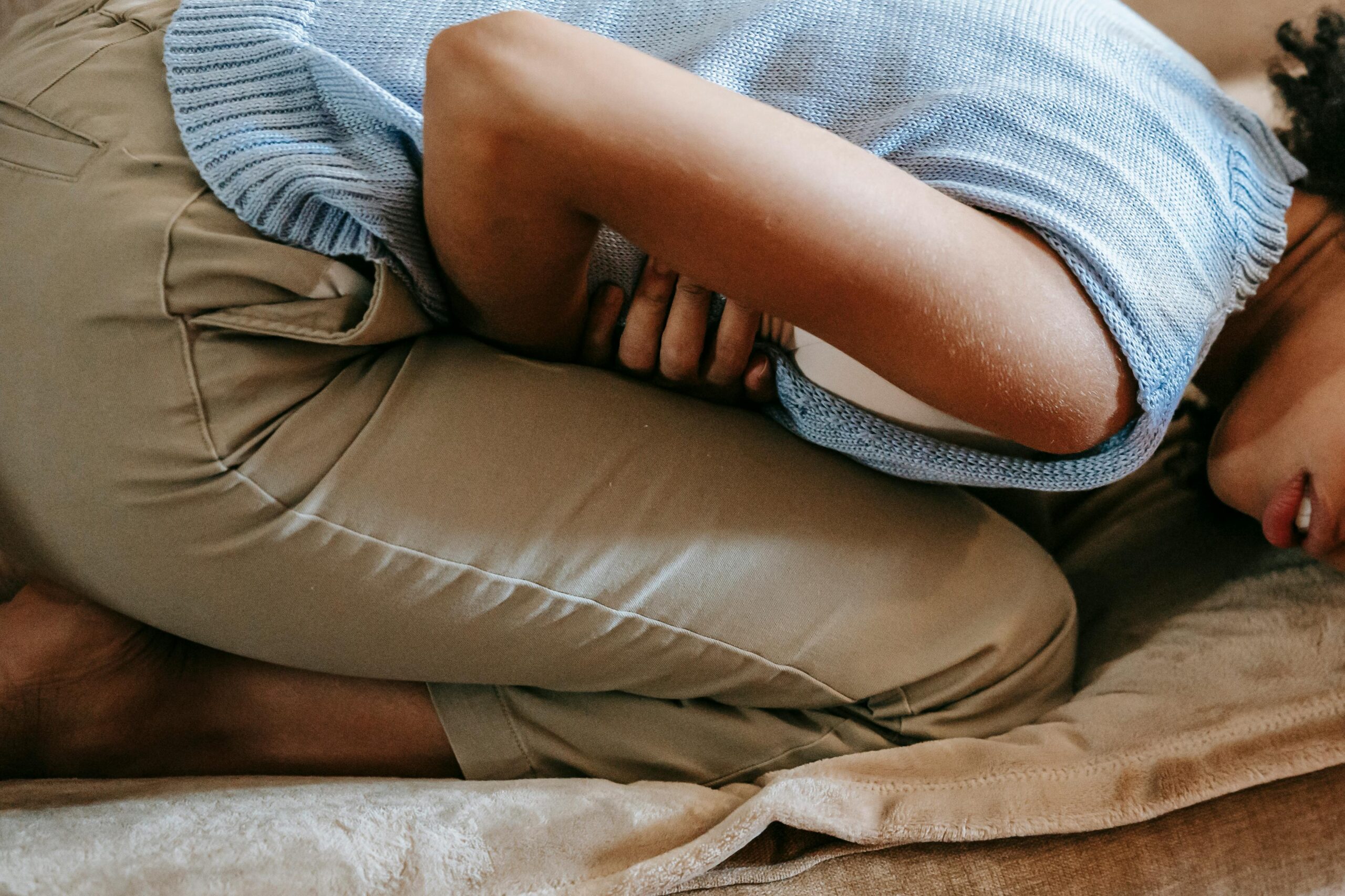 This Conversation Habit Could Be A Sign Of ADHD as a woman holds her stomach in the image in agony