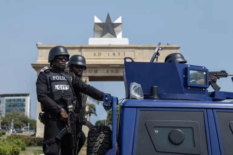 Members of Ghana security forces take part in a joint Show of Force Exercise in Accra, Ghana, 11 December 2025. The exercise featured the Ghana Police Service, Ghana Prisons Service, Ghana National Fire Service, the Customs Division of the Ghana Revenue Authority and the Immigration Service in collaboration with the Ghana Armed Forces, aimed at Police officers on security detail near a police vehicle, with the Ghana Black Star atop a building behind them. [FRANK KPORFOR/Epa]