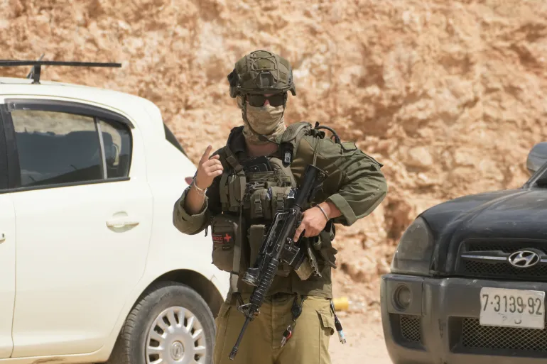 An Israeli soldier patrols the site of an attack by Israeli settlers on Palestinian properties in the occupied West Bank village of Qusra, Saturday, Aug. 29, 2026. (AP Photo/Majdi Mohammed)