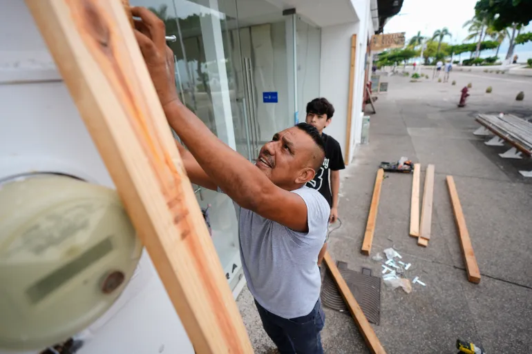 A man boards up a shop as Hurricane Simon approaches Puerto Vallarta, Mexico, Saturday, Oct. 10, 2026. (AP Photo/Fernando Llano)